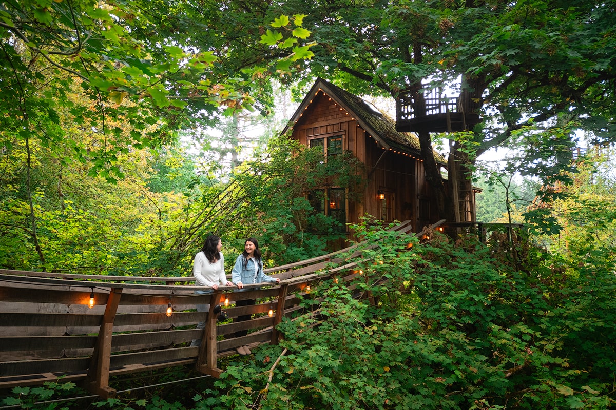 Renee and her friend standing on the swinging bridge outside of a Washington treehouse on a reading retreat.